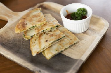 Tahta tabaklarda çıtır çıtır pizza ve sofra takımında sos kabı.