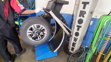 Bangkok, Tayland - 14 Ağustos 2021: Erkek tamirci garaj tekerleği değiştirme konseptinde araba tamircisi güvenlik kontrolü lastik tamir dükkanındaki tekerlek fındıklarını sıkılaştır.