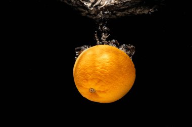 Suya düşen portakallar siyah zemine sıçrıyor ve sağlık için iyi..