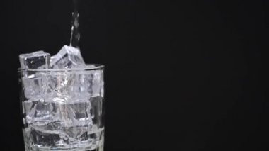 Siyah arkaplana karşı temiz bir bardağa su dök. kopyalama alanı ile