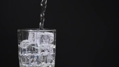 Siyah arkaplana karşı temiz bir bardağa su dök. kopyalama alanı ile