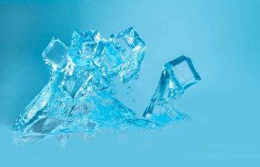 Mavi zemin üzerinde su sıçratan buz küpleri kavramı.