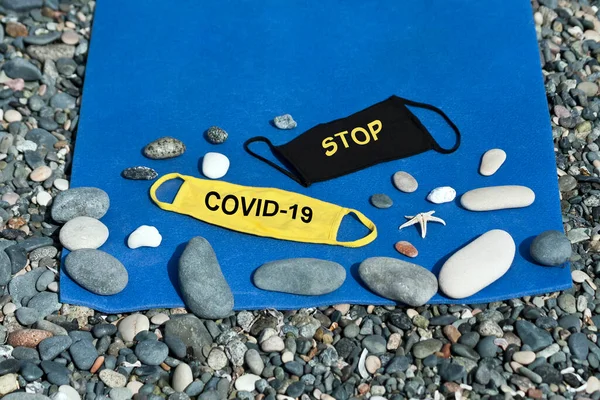 COVID-19 kavramını durdur: Plaj paspasındaki çakılların arasında iki koruyucu yüz maskesi 