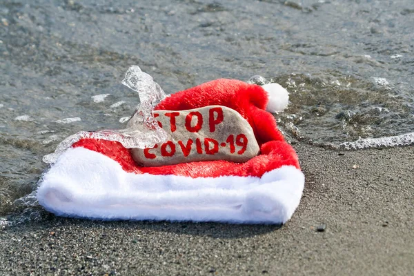 Santa Kapelusz Kamień Wiadomością Stop Covid Fali Morskiej Piaszczystej Plaży — Zdjęcie stockowe