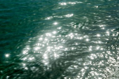 Dalgalanmış akuamarin deniz suyu güneş ışığında parlıyor.  