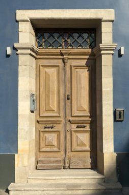 Eski moda ahşap bir ön kapı taştan bir kapı mavi bir duvarda güneş ışığı altında