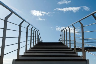 Mavi gökyüzünün önündeki beyaz bulutlu açık hava merdivenleri.