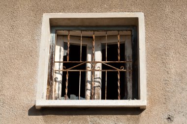 Bej taştan bir duvarın kırık ızgara penceresi 