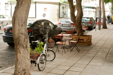 Limasol, Kıbrıs, 9 Kasım 2020: Eski kentte arabalar, ağaçlar ve kaldırımlı kafe masaları olan cadde