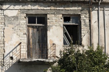 Ahşap kapısı ve kırık penceresi olan terk edilmiş eski tuğla ev duvarı. 