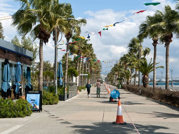 Limassol, Cyprus, March 2nd, 2021: Seafront promenade Molos with flag garlands as carnival decoration, social distancing signboard and traffic cones with barricade tape during the coronavirus quarantine