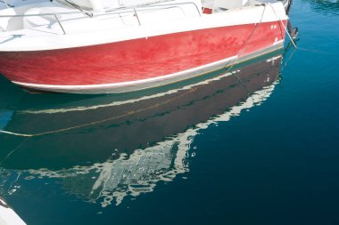 Kırmızı ve beyaz tekne ve mavi deniz suyundaki yansıması. 