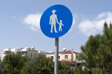 Kamu parkında gökyüzü önündeki yayalar için mavi trafik tabelası