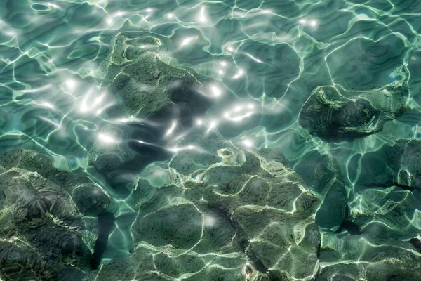 Transpatentes Aquamarin Meerwasser Schimmert Sonnenlicht Und Felsen Unter Wasser lizenzfreie Stockbilder