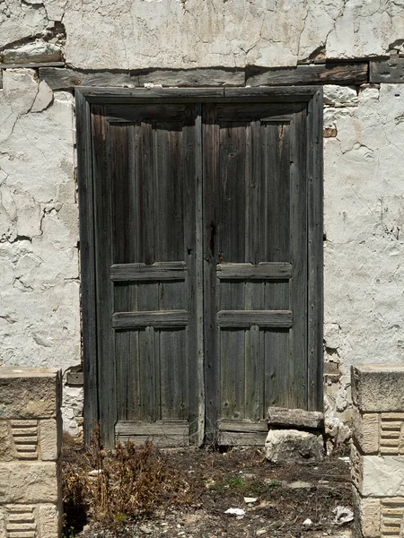Eski ahşap ön kapı harabe taş duvarda. 