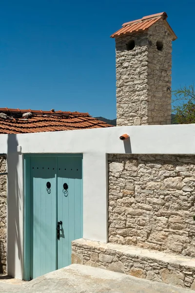 蓝天前传统村屋的蓝门 白色石柱烟囱和褐色砖瓦屋顶 免版税图库照片