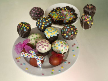 Süslü Paskalya yumurtaları ve beyaz kremalı ve renkli konfetiyle ev yapımı çikolatalı kekler.