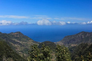 Dağlı manzara ve mavi gökyüzü ve bulutların üzerindeki yeşil ağaçlar