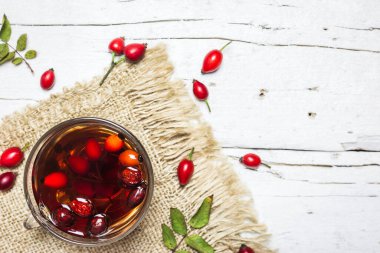 Kırsal ahşap arka planda gül kalçalı bir fincan çayın yakın plan fotoğrafı, üst manzara. Sonbahar vitamin içeceği.