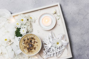 Evde bir fincan kahve, mumlar ve çiçeklerle sıcak sabahlar. Tahta bir tepside. Blogcular için düz konum.