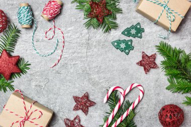 Noel kompozisyonu. Noel hediyeleri, süsler, her zaman yeşil olan ağaç, şeker kamışı ve gri taş arka planda kurdeleler. Düz konum, üst görünüm, kopyalama alanı.
