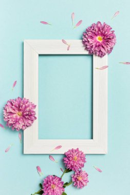 Çiçek kompozisyonu. Boş fotoğraf çerçevesi ve pastel mavi arka planda çiçekler. Sevgililer günü, anneler günü, kadınlar günü, bahar konsepti. Düz konum, üst görünüm, kopyalama alanı.