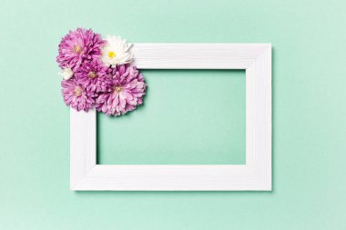 Çiçek kompozisyonu. Boş fotoğraf çerçevesi ve pastel yeşil arka planda çiçekler. Sevgililer günü, anneler günü, kadınlar günü, bahar konsepti. Düz konum, üst görünüm, kopyalama alanı.