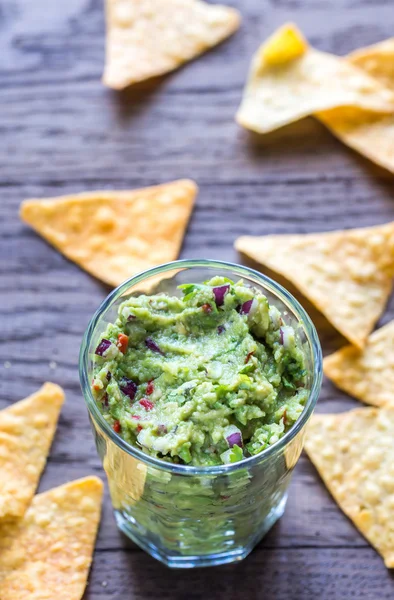 Guacamole s tortilla chipsy na dřevěný stůl — Stock fotografie