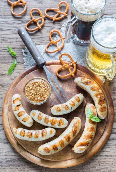 Сосиски на гриле с крендельками и кружками пива — стоковое фото