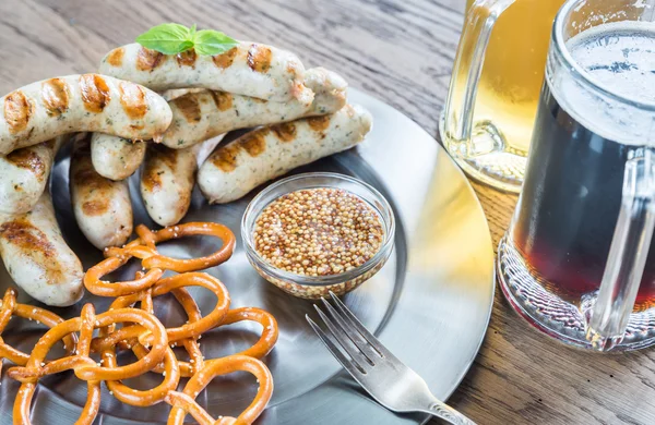 Salsichas grelhadas com pretzels e canecas de cerveja — Fotografia de Stock