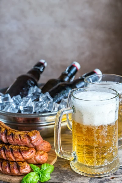 Сосиски на гриле и кружки пива — стоковое фото
