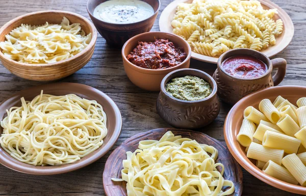 Pasta met verschillende soorten saus op de houten achtergrond — Stockfoto