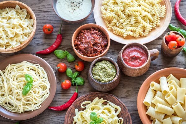 Pasta met verschillende soorten saus op de houten achtergrond — Stockfoto
