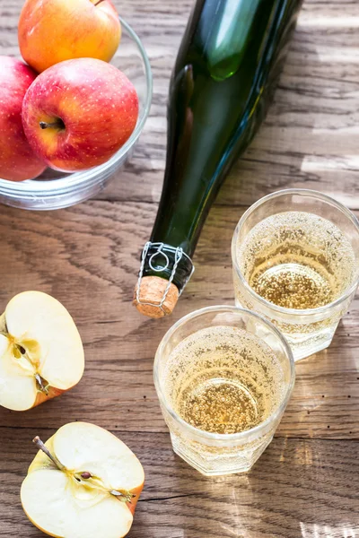 Bottle and two glasses of cider on the wooden background — Stock Photo, Image