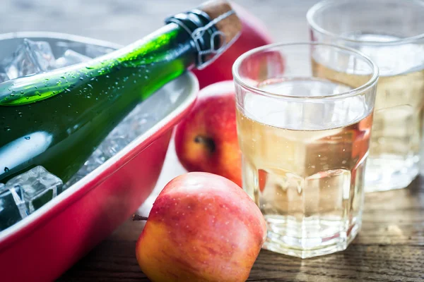 Bottle and two glasses of cider on the wooden background — Stock Photo, Image