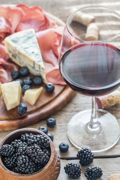 Стакан красного вина с антипасто на деревянном столе — стоковое фото