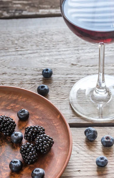 Copo de vinho tinto com bagas frescas na mesa de madeira — Fotografia de Stock