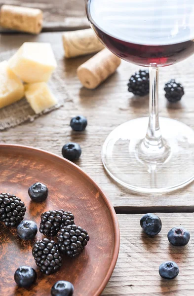 Стакан красного вина со свежими ягодами на деревянном столе — стоковое фото