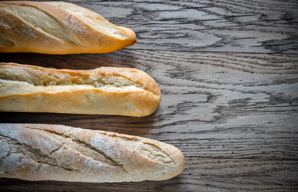 Tres baguettes en el fondo de madera —  Fotos de Stock