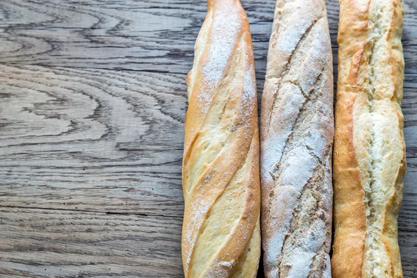 Tre baguette sullo sfondo di legno — Foto Stock