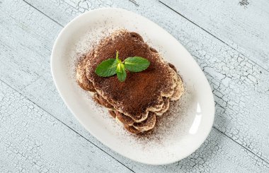 Beyaz servis tabağında tiramisu porsiyonu