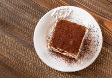 Tahta arka planda bir porsiyon tiramisu italyan tatlısı