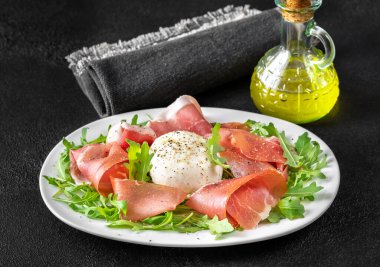 Prosciutto, mozzarella ve servis tabağında taze roka.