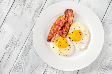 Beyaz tabakta pastırmalı yumurta ve pastırma.