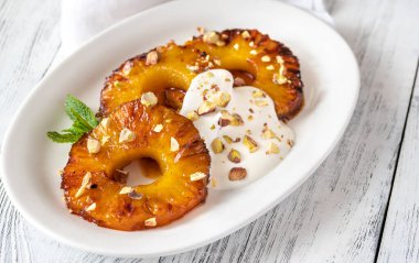 Caramelized pineapple with whipped cream and pistachios on the serving plate