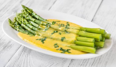 Servis tabağında Hollandaise soslu kuşkonmaz.