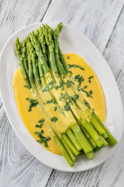 Servis tabağında Hollandaise soslu kuşkonmaz.