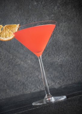 Kurutulmuş portakal dilimiyle süslenmiş Cosmopolitan kokteyli.