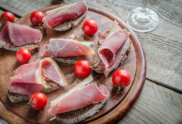 Ahşap tahta üzerinde İtalyan jambon dilimleri — Stok fotoğraf