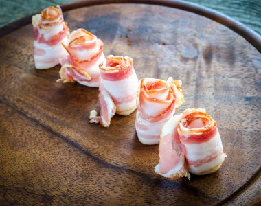 ahşap tahta üzerinde domuz pastırması şeritler haddelenmiş